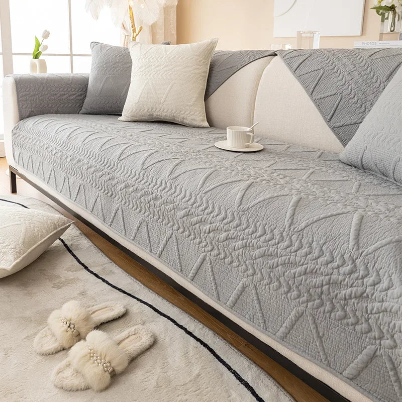 A light gray washed cotton sofa cover with a quilted texture and non-slip backing displayed on a sofa.
