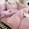 A close-up of a pink luxurious washed cotton bed linen set featuring pillows and a duvet on a bed.