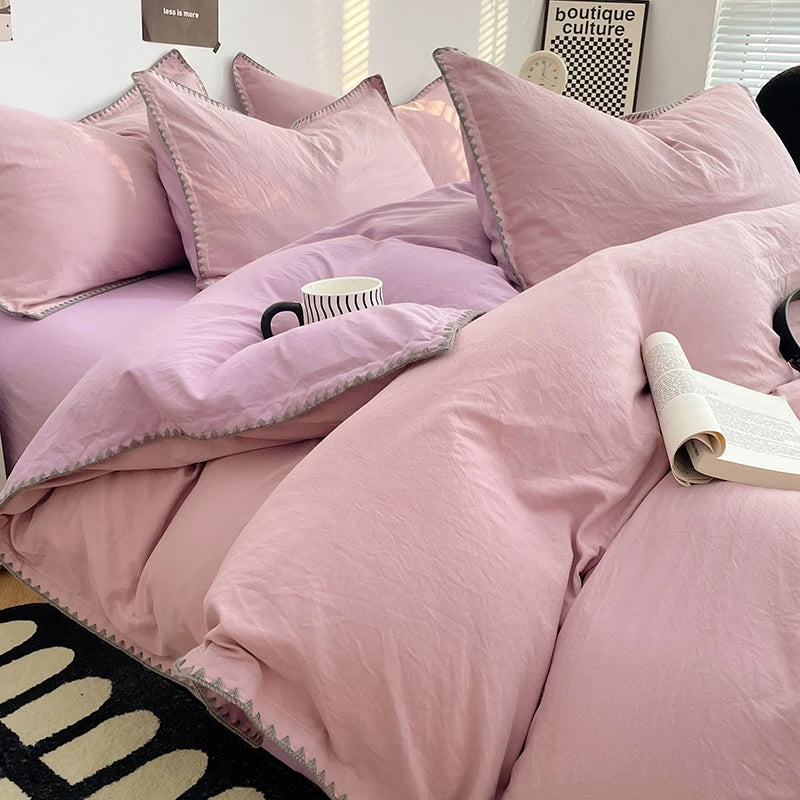 A close-up of a pink luxurious washed cotton bed linen set featuring pillows and a duvet on a bed.