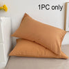 A single tan cotton pillowcase with an envelope closure resting on a light surface.