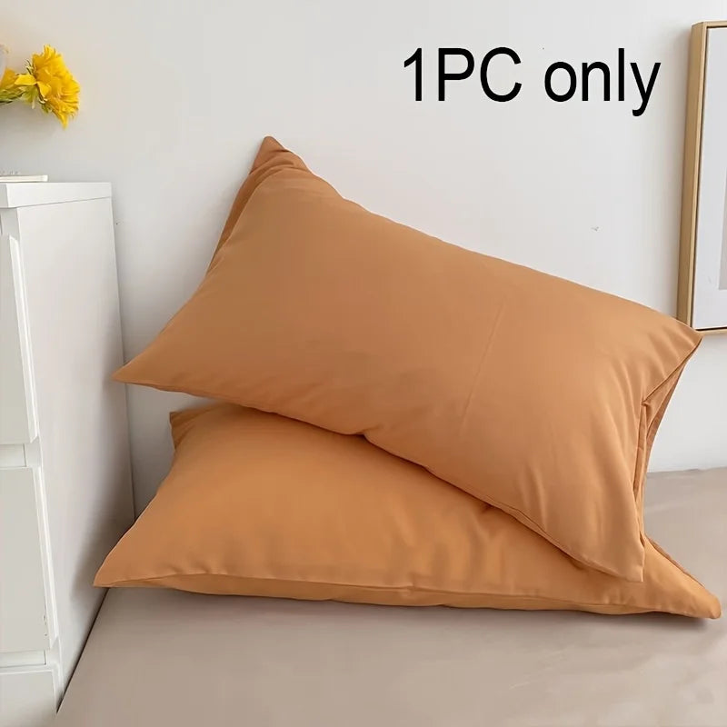 A single tan cotton pillowcase with an envelope closure resting on a light surface.