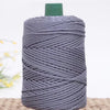 A spool of gray crochet ice rope with a green cap resting on a woven mat.