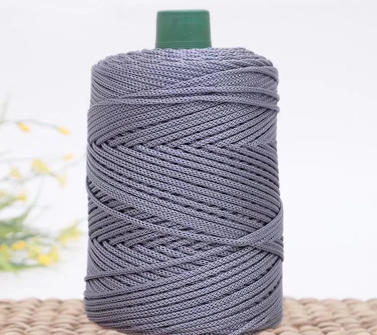 A spool of gray crochet ice rope with a green cap resting on a woven mat.