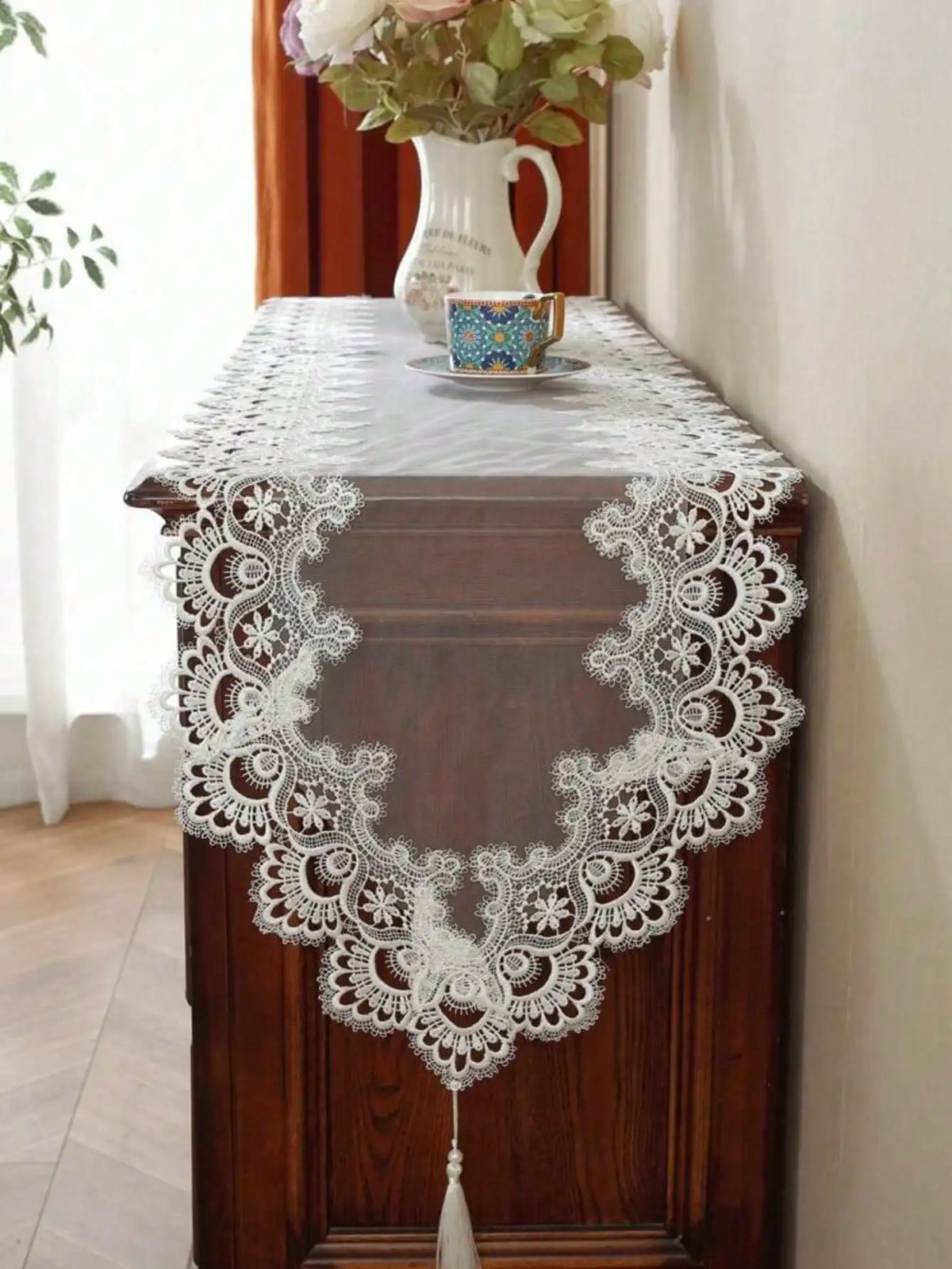 A dark wood cabinet with a white lace table runner and a small decorative plate on top.
