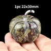 A natural stone pumpkin figurine with a textured, mottled green and brown appearance is held in a hand.