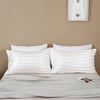 White and gray striped pillow covers on a bed with white pillows and a light gray duvet.