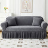 A gray jacquard elastic sofa cover featuring a pleated skirt and decorative texture.