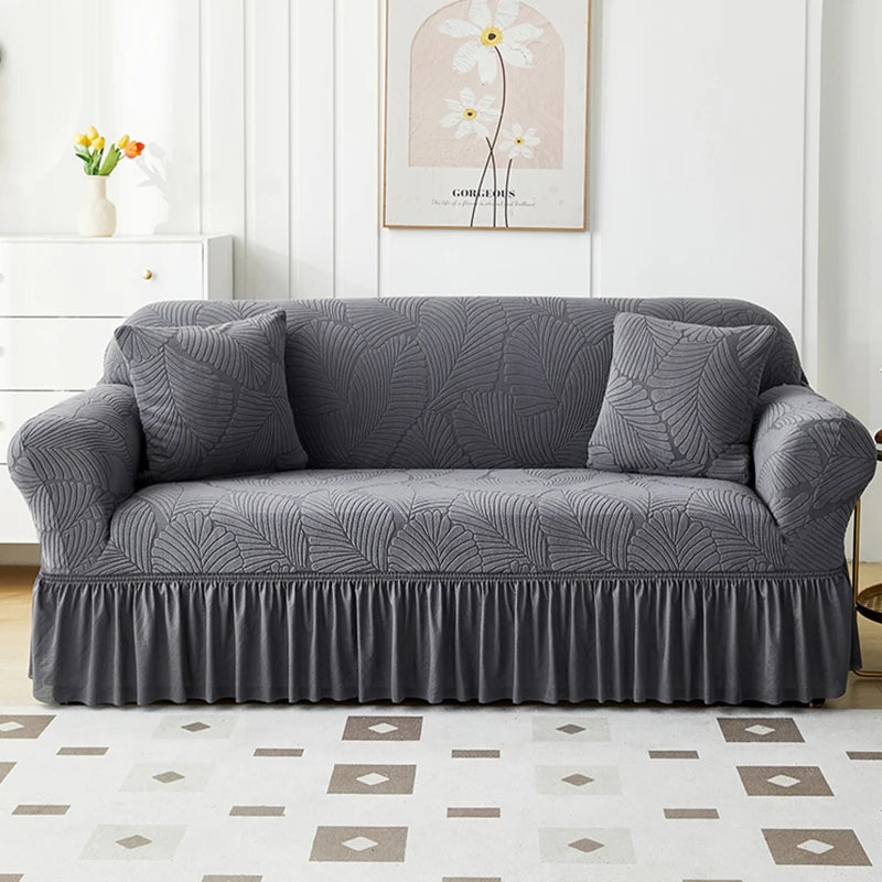 A gray jacquard elastic sofa cover featuring a pleated skirt and decorative texture.