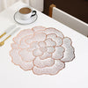 A set of gold-plated peony coasters with delicate floral patterns resting on a white table.