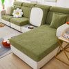 A light green leaf pattern sofa slipcover with white cushions and decorative pillows in a bright living room.
