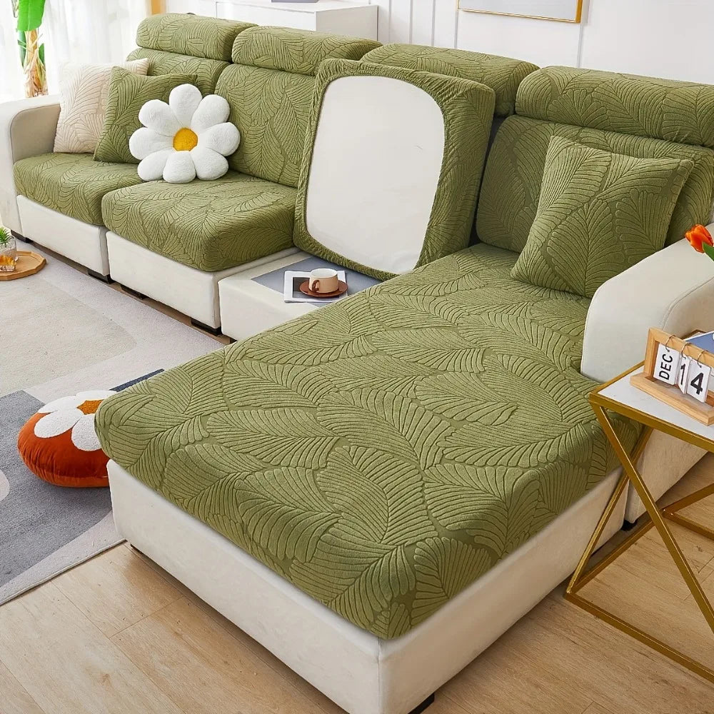 A light green leaf pattern sofa slipcover with white cushions and decorative pillows in a bright living room.