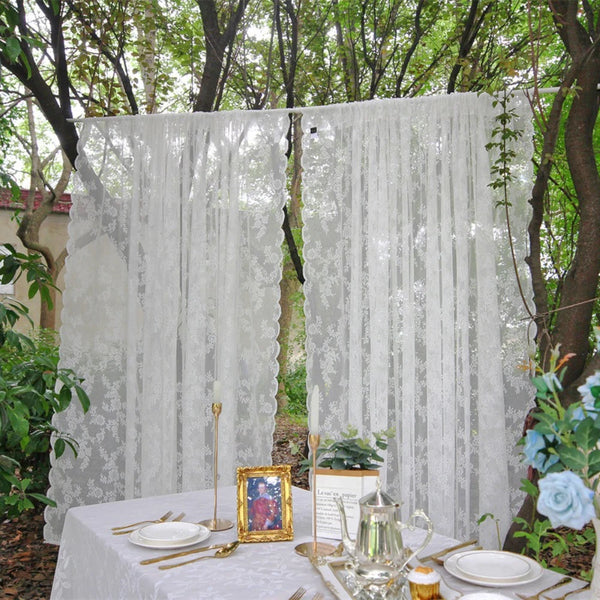 Vintage floral lace curtains hanging outdoors on a table setting with gold accents