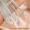 A hand holds a bundle of big-eye steel sewing needles for embroidery and crafting.