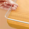 A hand is placing a clear PVC table protector mat onto a wooden surface.