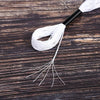 A spool of white embroidery floss with a black tip and loose threads lying on dark wood.