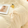 A light beige princess chiffon duvet cover set with a white pearl necklace and a framed photo.