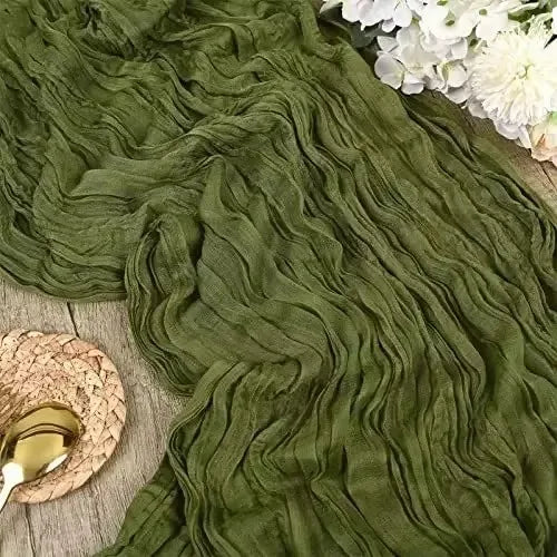 A close-up of a moss green rustic gauze table runner draped elegantly with white flowers.