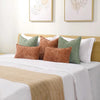 A collection of decorative chenille throw pillow covers in shades of green, brown, and white on a bed.