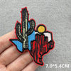An embroidered iron-on patch featuring a stylized silhouette of a cowboy hat and landscape in red, blue, and black thread.