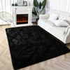 A black tie-dyed plush floor mat placed in front of a white fireplace and a white sofa.