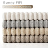 A stack of fluffy, striped bunny fabric covers for pillows in beige and gray tones.