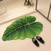 A large green leaf-shaped quick-dry bathroom mat with a rubber backing placed on a light surface.