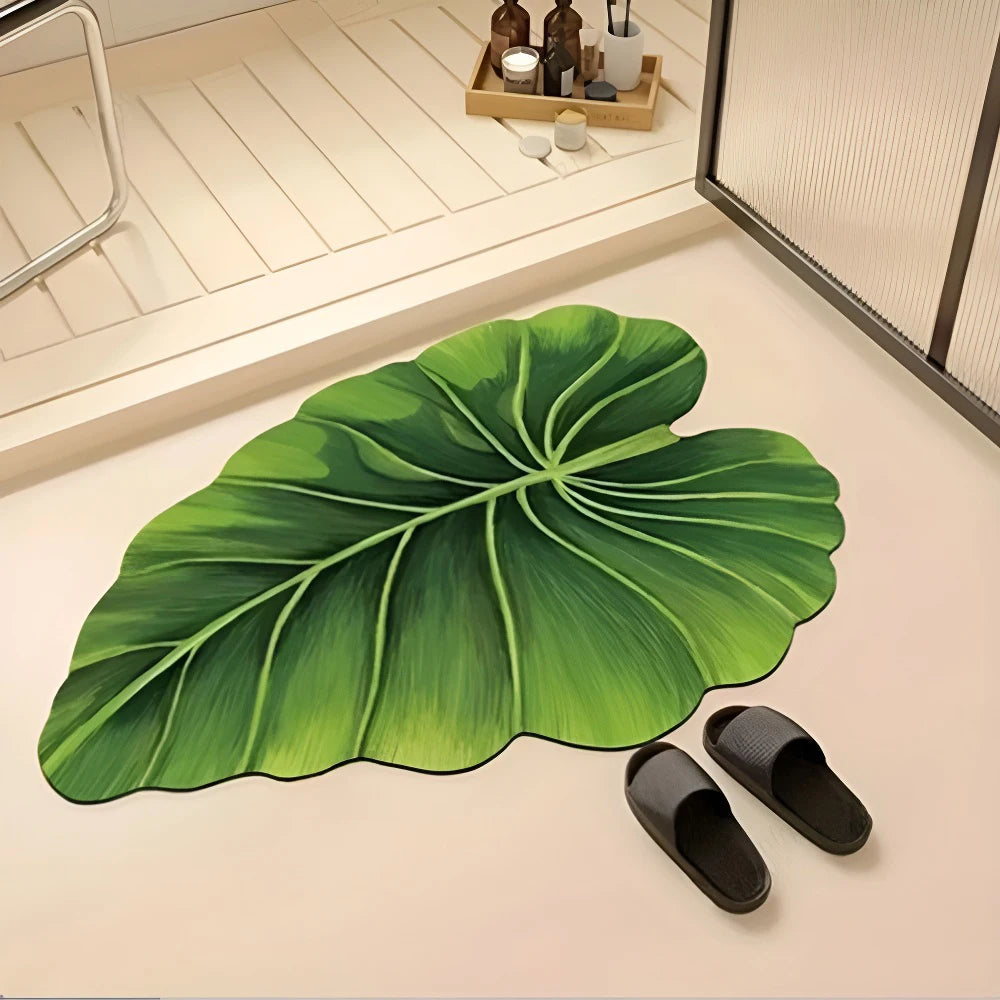 A large green leaf-shaped quick-dry bathroom mat with a rubber backing placed on a light surface.