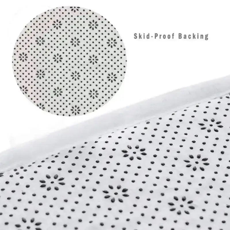 Close-up view of a white mat with a black sun motif pattern, showing skid-proof backing.