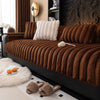 A dark brown, ribbed plush sofa seat cushion with a white accent cushion and fluffy white decor on a modern sofa.