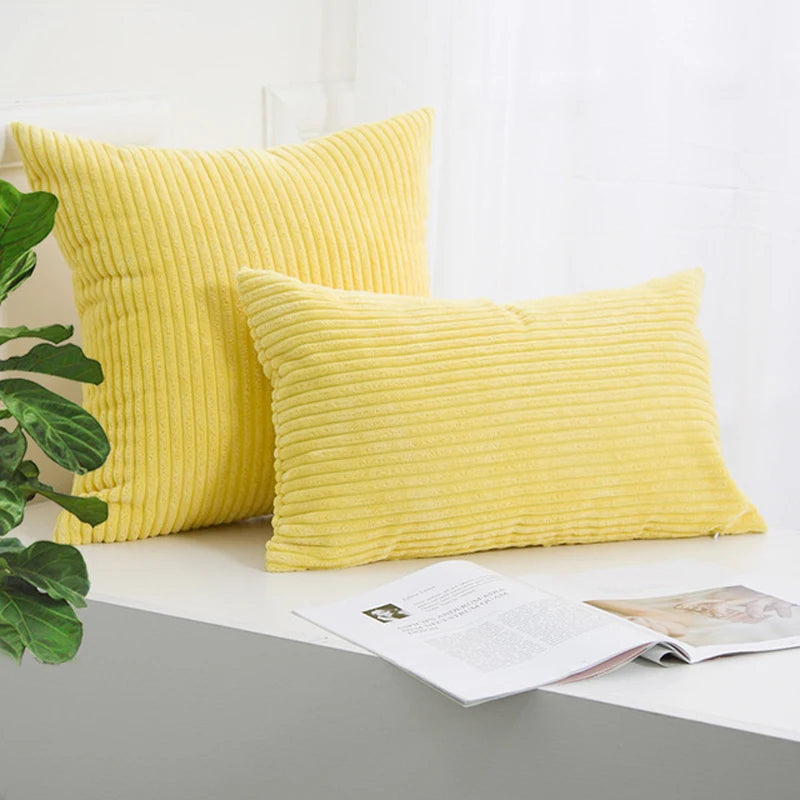 A stack of bright yellow corduroy striped throw pillows resting on a white surface.