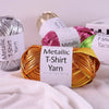 Spool of metallic gold T-shirt yarn lying on a white fabric surface.