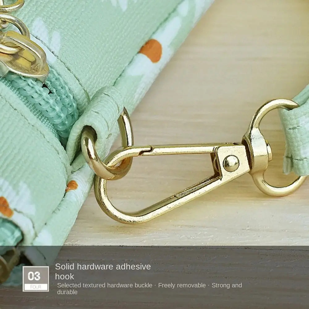 Gold hardware hook on a light green PU leather coin purse with a wrist strap