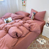 A pink duvet cover set with matching pillowcases and a stuffed animal on a bed.