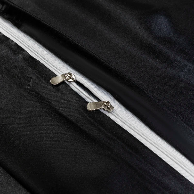 Close-up of a black satin bedding set featuring a silver zipper detail.