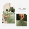 A close-up of a sage green stretchable elastic sofa cover showing the textured fabric and anti-slip design.