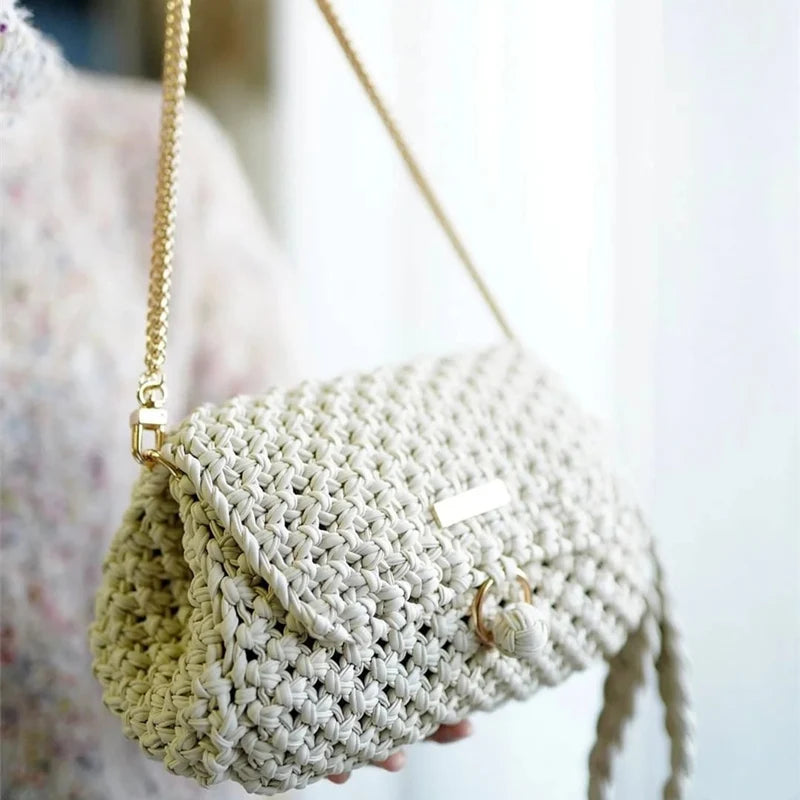 A light beige crocheted pouch made from flat thread yarn being held by a person.