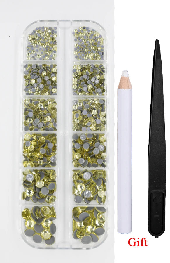 A clear plastic container holding a set of crystal hot fix rhinestones and an applicator tool for crafting