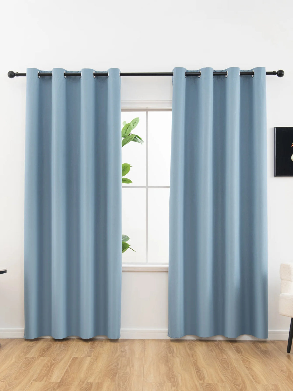 Light blue blackout curtains hanging in a window frame.