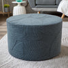 A round, textured gray jacquard ottoman footrest slipcover resting on a light rug.