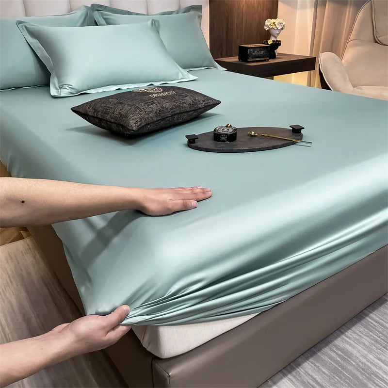 A light blue fitted bed sheet is draped over a bed, with hands adjusting the fabric.