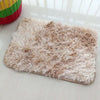 A rectangular beige faux fur rug is displayed on a white surface.