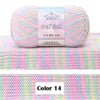 A ball of pink and blue gradient yarn labeled as DAHUAFANGZHI silk yarn resting on a pink striped knitted fabric.