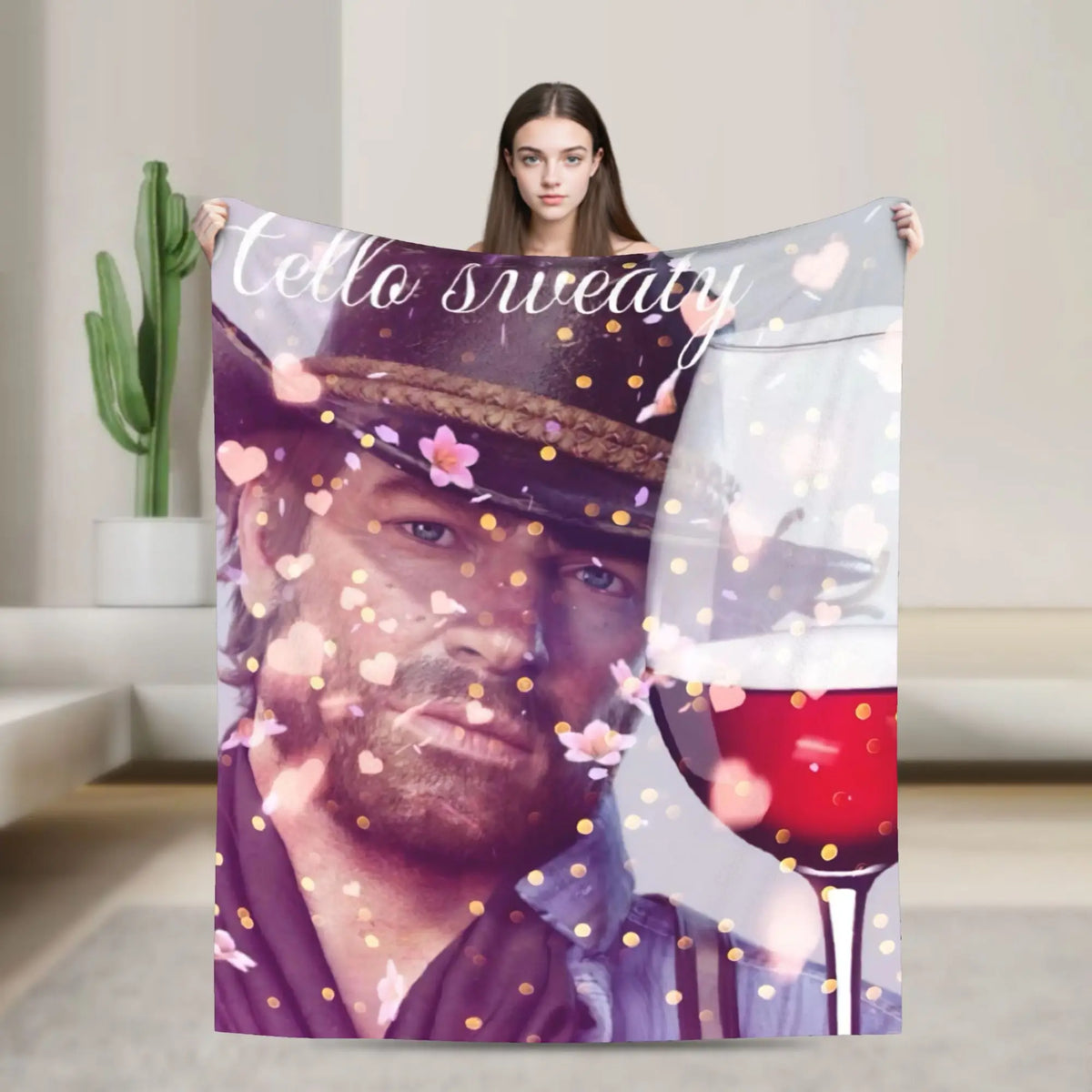 A woman holds up a textile featuring a portrait of a man in a hat and a glass of red wine.