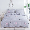 A gray bedding set featuring a pink heart print duvet cover and pillowcases.