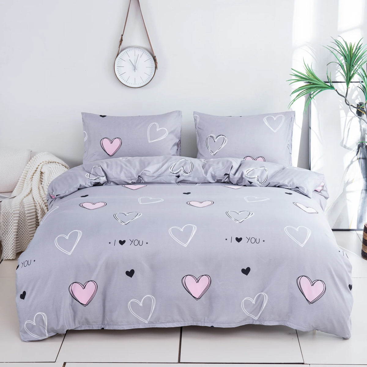 A gray bedding set featuring a pink heart print duvet cover and pillowcases.