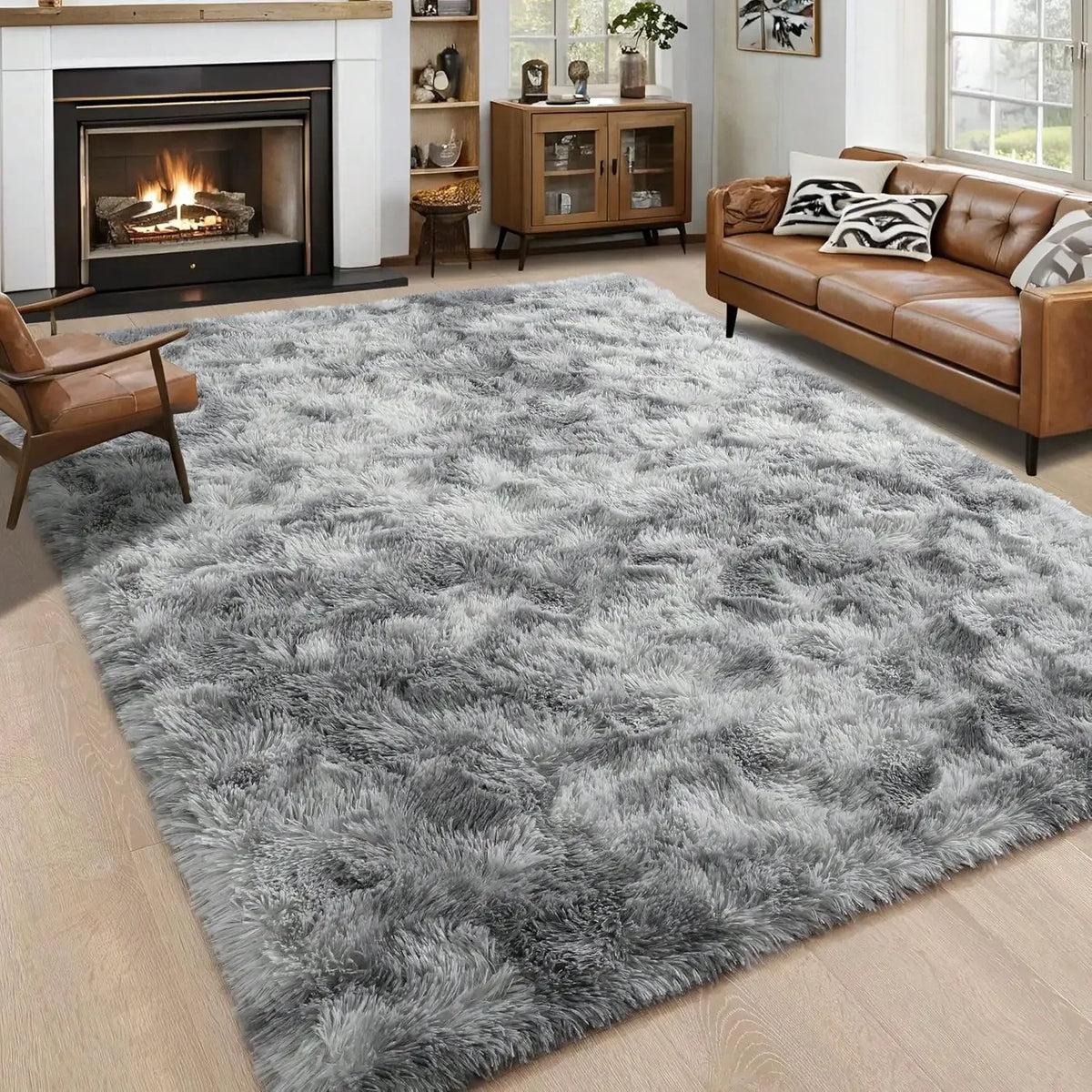 A plush gray long-pile area rug placed in a living room with a leather sofa and fireplace.