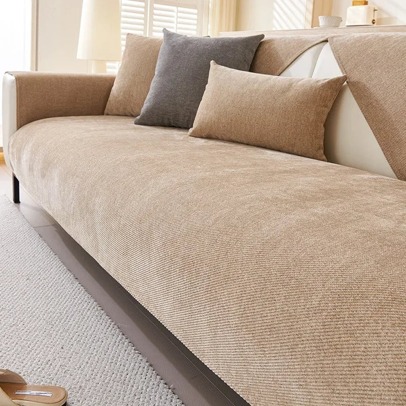 A beige waterproof anti-scratch sofa protection cover is draped over a light-colored sofa with gray and tan accent pillows.
