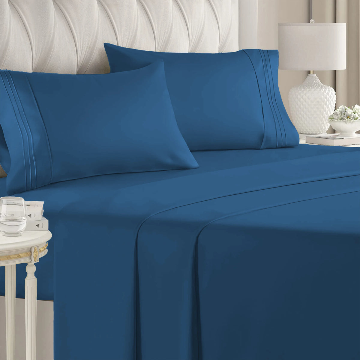 A navy blue luxury microfiber bed sheet set with deep pockets draped on a bed.
