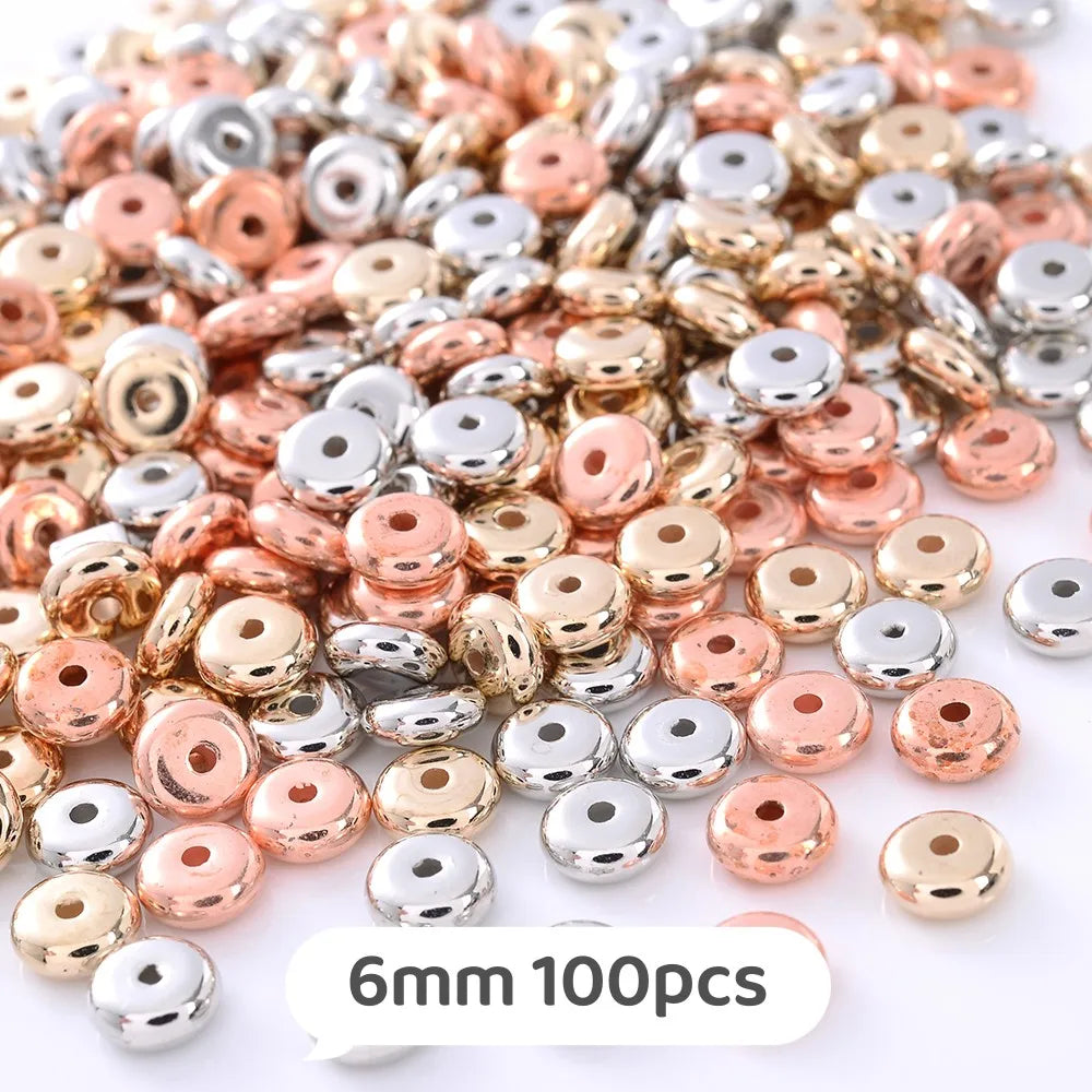 A pile of small, round geometric acrylic beads in various shades of rose gold and silver.