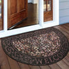 A semi-circular mosaic floor mat with a vintage floral print placed on a wooden floor near a glass door.